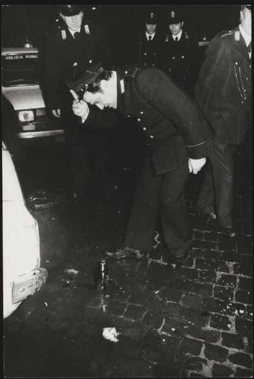 A policeman inspects a petrol bomb