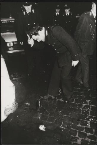 A policeman inspects a petrol bomb