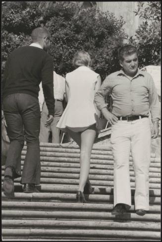 An Italian 'Pappagalli' man talks to a female tourist as they walk up the Spanish Steps, Rome