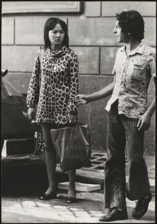 An Italian 'Pappagalli' man approaches a female tourist at a street crossing