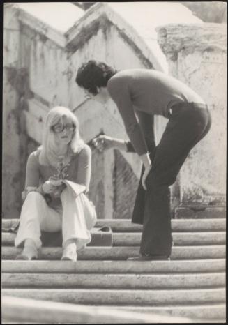 An Italian 'Pappagalli' man approaches a femlae tourist on the steps of Trinità dei Monti, Rome