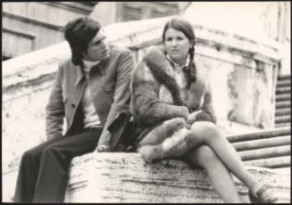 An Italian 'Pappagalli' man sits with a  female tourist by Trinità dei Monti, Rome