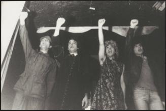 Four men during an performance, dressed in various theatrical costumes