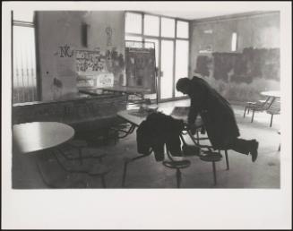 A man in the classroom of the Architecture Faculty at a University painted with political slogans 