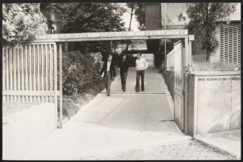 Three students walk from the library of a university