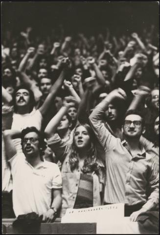 Young people at an unidentified rally, all cheering with their fists raised in the air