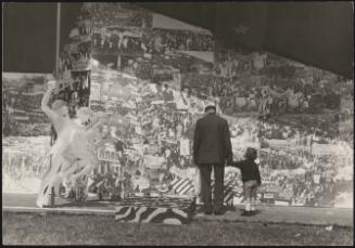 An old man and a child look at pictures of communist propaganda on panels, 1973
