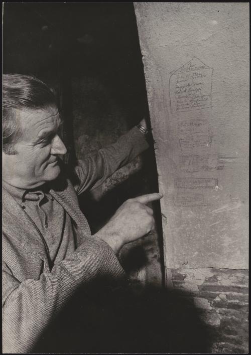 One of the survivors of the massacre at Marzabotto points out carved-out signatures left by prisoners on a wall