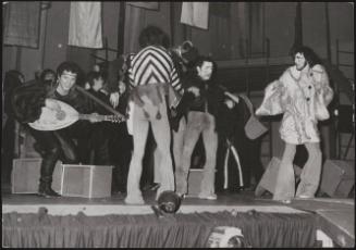 Young hippies in fancy dress playing instruments on stage