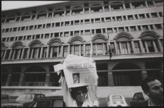 A woman holds a newspaper with the headline 'Victory for DC (Christian Democratic Party)'/'Change in Liberty', standing in the Piazza don Sturzo, Rome