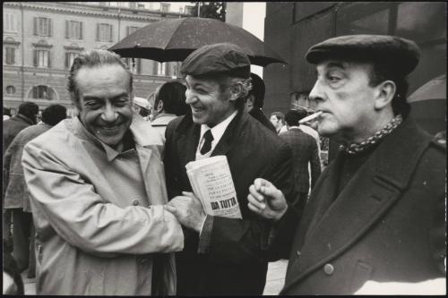 The painter Renato Guttuso (left) is greeted by friends at an event in the rain