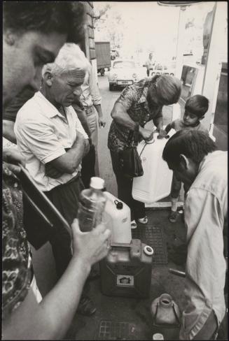 People collecting petrol in containers during a petrol station strike.