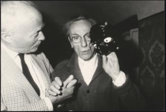 Eduardo De Filippo and companion. De Filipo holds up a mask.