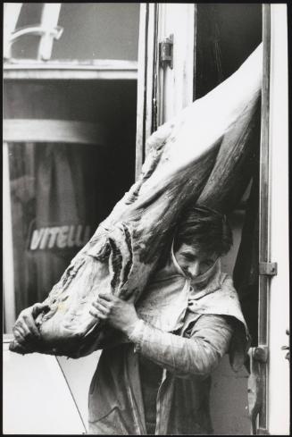 The arrival of frozen beef; a man carries the carcass out from the lorry