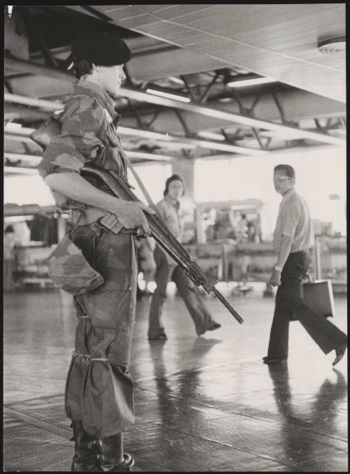 An armed guard stands as security in an airport foyer 