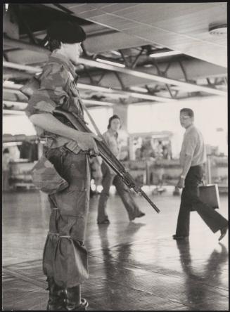 An armed guard stands as security in an airport foyer 
