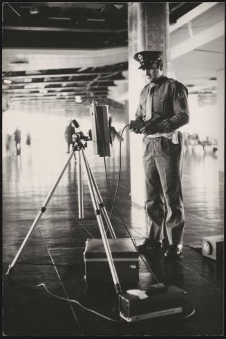 A security guard tests a device in an airport foyer