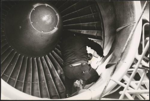 A man checks an aeroplanes turbine engine with a torch