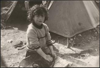 A young girl washes an item of clothing on  a washboard in a refugee camp after the destruction of the Belice earthquake in Sicily 1968