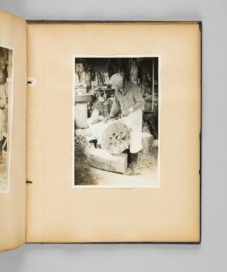 [Carver Louis Jobin uses a tool on a large wooden religious statue] Page 65 of Ste Anne de Beaupré; from collection of Canadian albums compiled by Edith S. Watson, 1890s-1930s