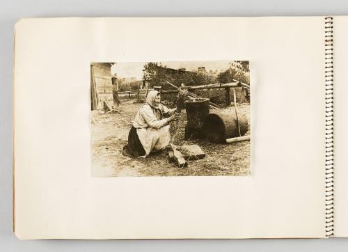 [Woman in headscarf squatting and holding bundle of straw, page 30 of The Doukhobors I album