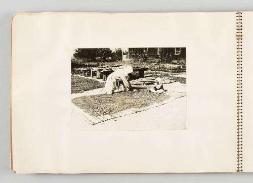 [Woman spreading grain on carpet with seated child, page 20 of The Doukhobors I album]