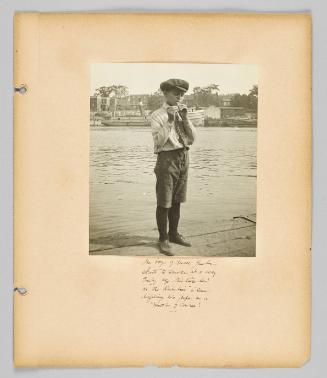 The boys of rural Quebec start to smoke at a very early age. This little lad on the Richilieu is seen lighting his pipe as a matter of course! [Page 45 of Children album]

