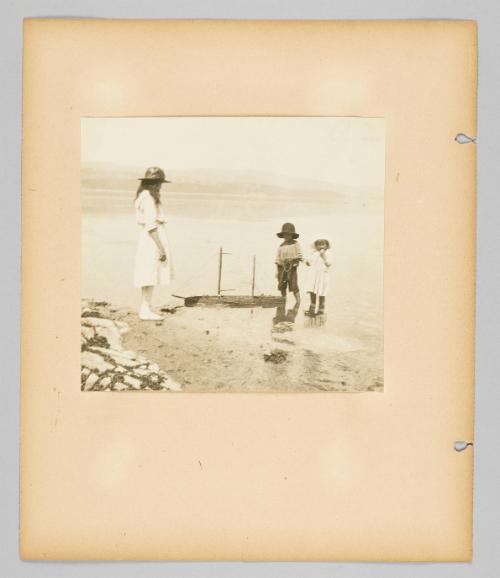 [Children playing with toy boat on shore, page 34 of Children album]