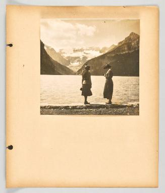 [Two women stand together at the shore of Lake Louise] [Page 21 of Banff, Lake Louise album]