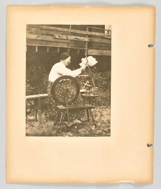 [Elderly woman spins flax yarn barefoot in the yard] [Page 24 of The Doukhobors II album]