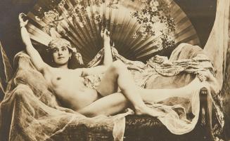 [Woman seated on bed with large decorated fan]