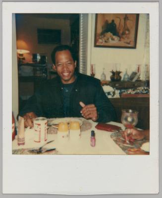 [Man at dinner table smiling with can of beer in front of him]
