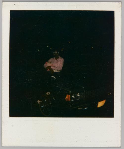 [Woman holding plush toy of a duck sitting on car]
