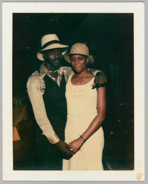 [Man and woman in sun hats holding hands and smiling]
