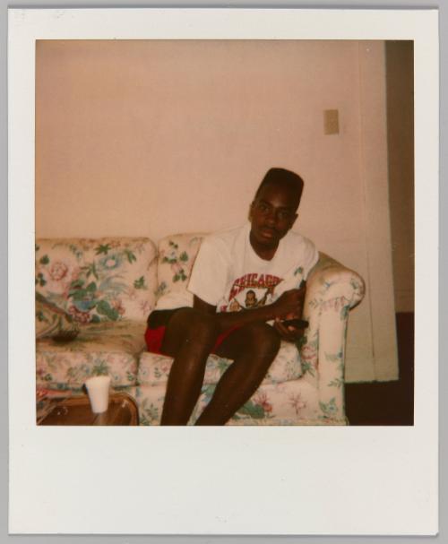 [Adolescent boy seated on floral couch wearing Chicago graphic t-shirt]
