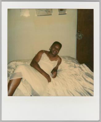 [Person in nightgown reclining on bed with their arm crossed over their waist, door to the right]