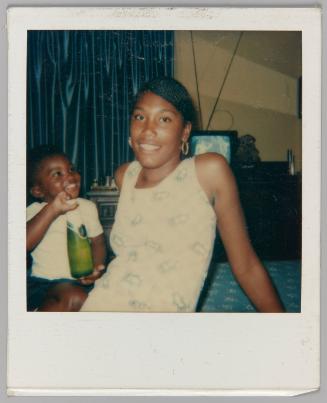 [Woman and child smiling; child holding an unopenned bottle of beer]
