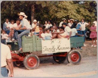 [Green wagon filled with children with sign that reads "W H Family Reunion" ]