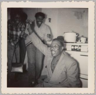 [Man with eyes closed, mouth open and hand raised in air with two women cheering behind him]
