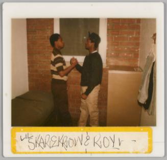 Lil Skarekrow & Roy [Two teenage boys facing each other and doing a handshake, they are in front of a brick wall]