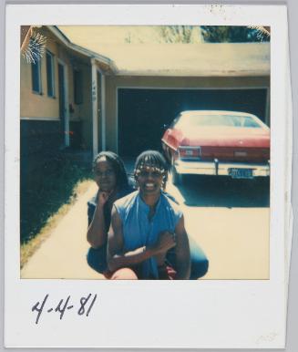 4-4-81 [Young woman and adolescent boy with beaded braids posing in driveway]