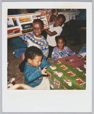 [Group of four children opening their Christmas gifts]