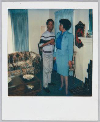 [Women in blue pencil skirt and matching blazer looking at adolescent boy standing next to her]