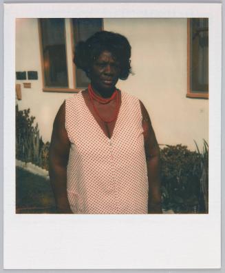 [Woman in red and white polkadoted dress and red necklace]