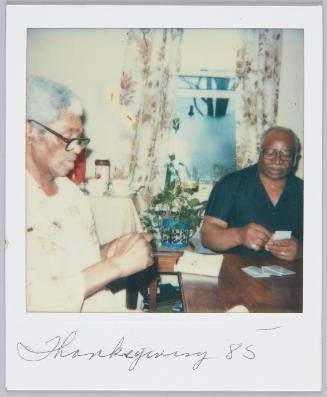 Thanksgiving 85 [Elderly men playing a game of cards at table, both are wearing glasses]
