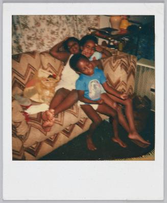 8-27-84 [Three kids sitting on top of each other in couch corner]
