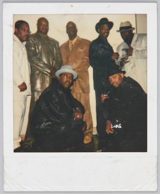 [Group of men in stylish suits posing, man on far right wears all white]