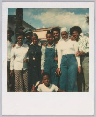 [Group of women and men standing outside on a slighty cloudy day, everyone is wearing blue and white]