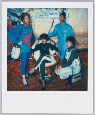 [Four women posing in front of painted sign 'Saints Ladies']