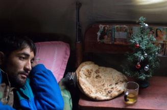 An Afghan National Army soldier lays in his bed beside his assault rifle, bread, tea and a small Christmas tree during the morning on the second day of EID while taking a break from the fighting to celebrate the second EID also known as the Festival of Sacrifice at a Forward Operating Base on the front lines in Zhari District located west of Kandahar City, Afghanistan. Many of the Afghan soldiers serving with Canadian Troops considered EID like their form of Christmas. There are two celebrations of EID during the second it is common to sacrifice an animal, which is to commemorate and celebrate the sacrifice of the Prophet Abraham also known as Ibrahim